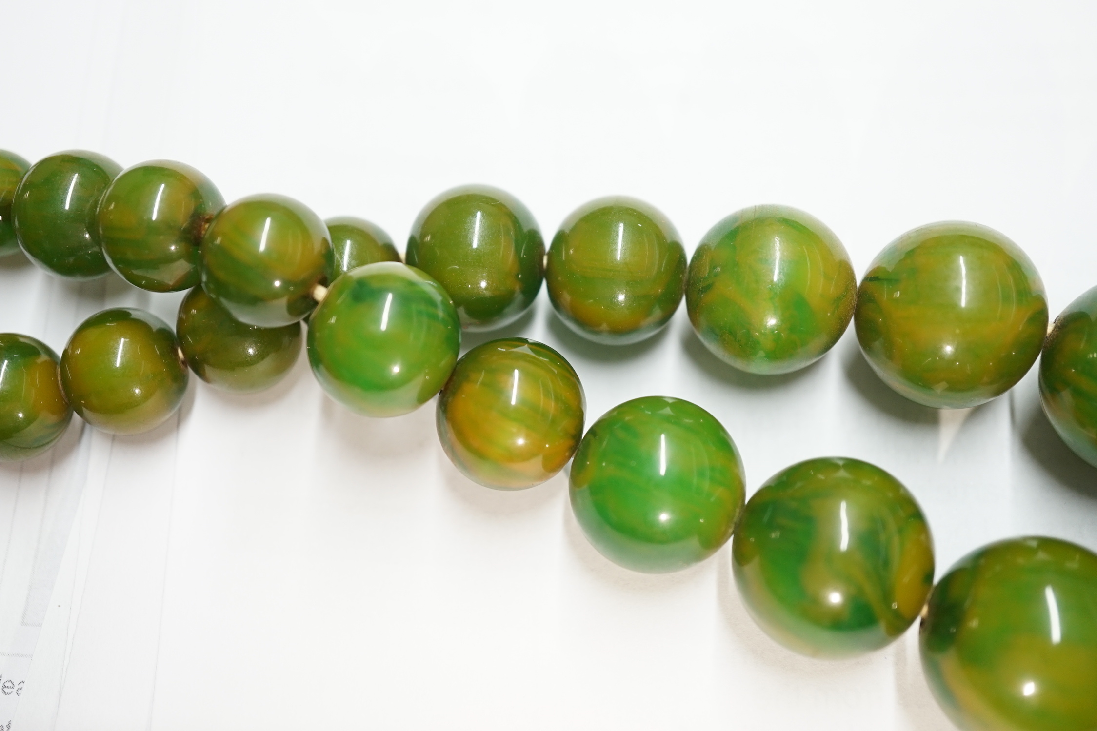 A single strand graduated simulated cherry amber necklace, one other necklace and some loose beads